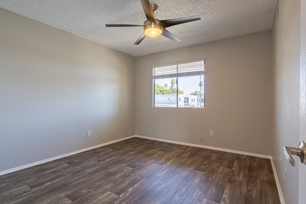 an empty bedroom with a ceiling fan and a window