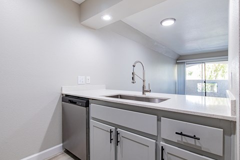 A white kitchen with a sink and a dishwasher.