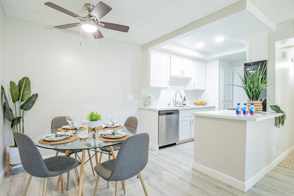a dining area with a table and chairs and a kitchen in the background
