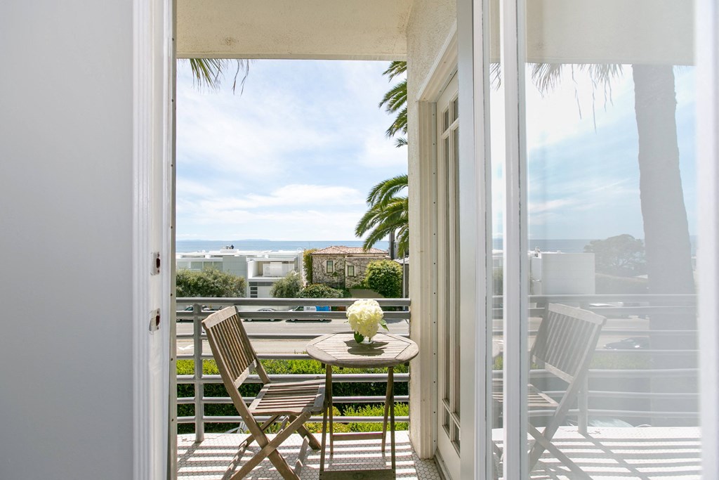 a balcony with a table and chairs and a view of the ocean
