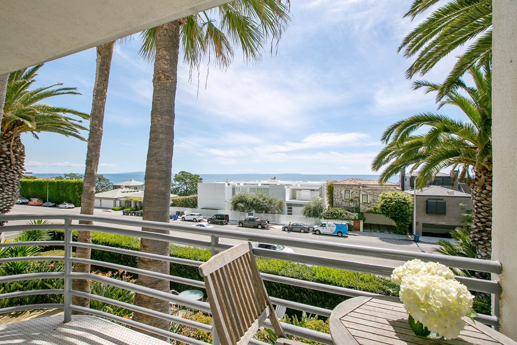 a balcony with a table and a chair and palm trees