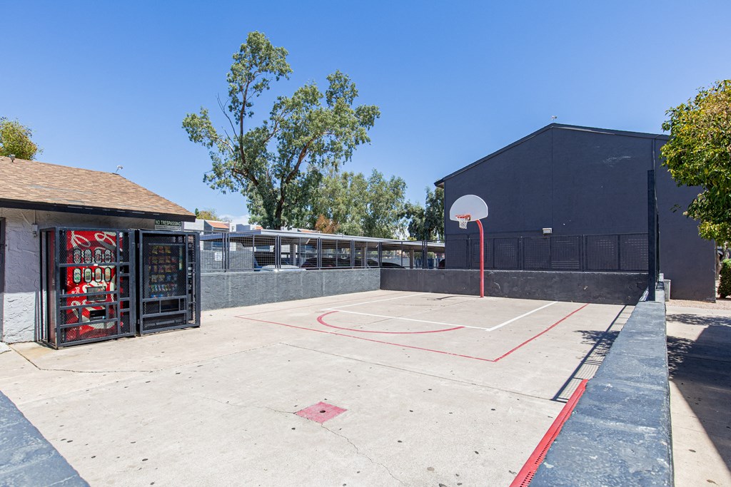 a basketball court in the middle of a parking lot next to a building