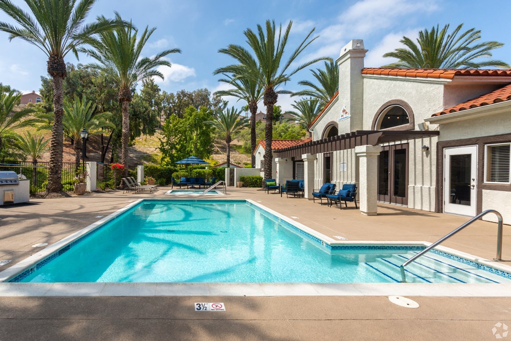 a swimming pool in front of a house with palm trees