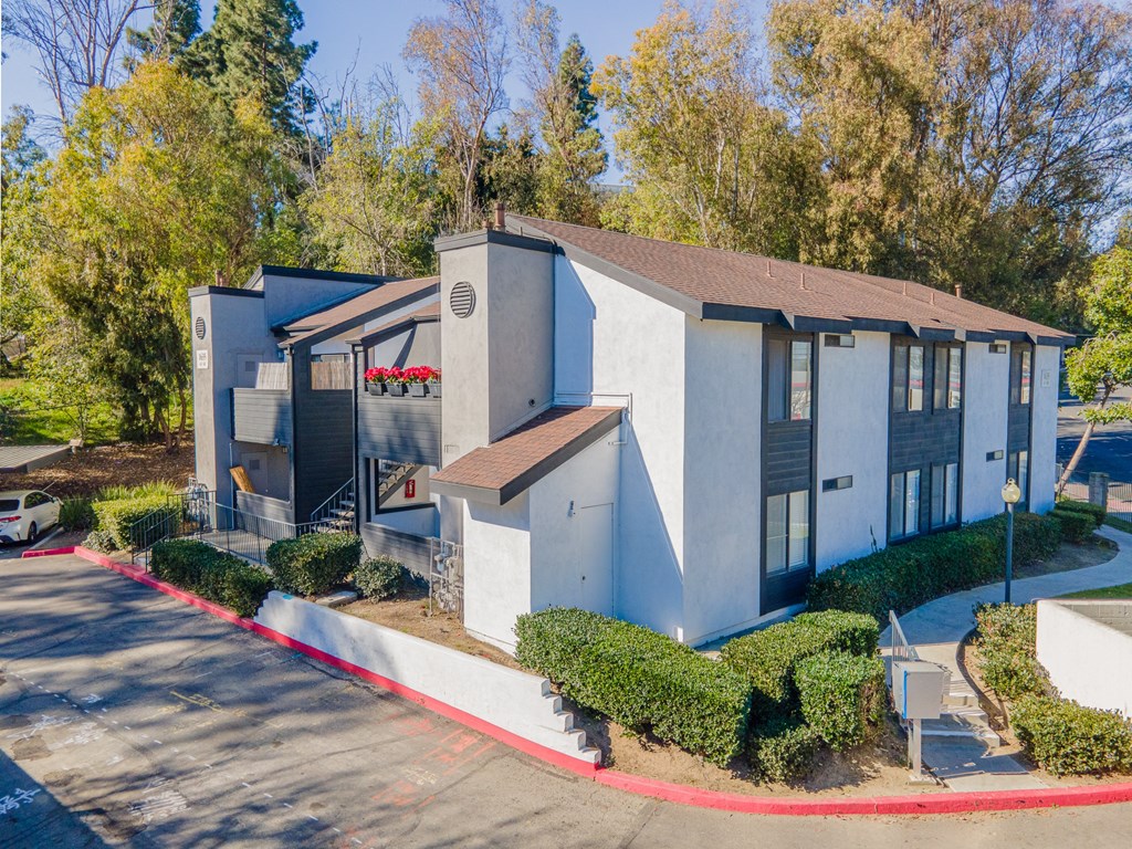 a white and blue building with a parking lot and trees