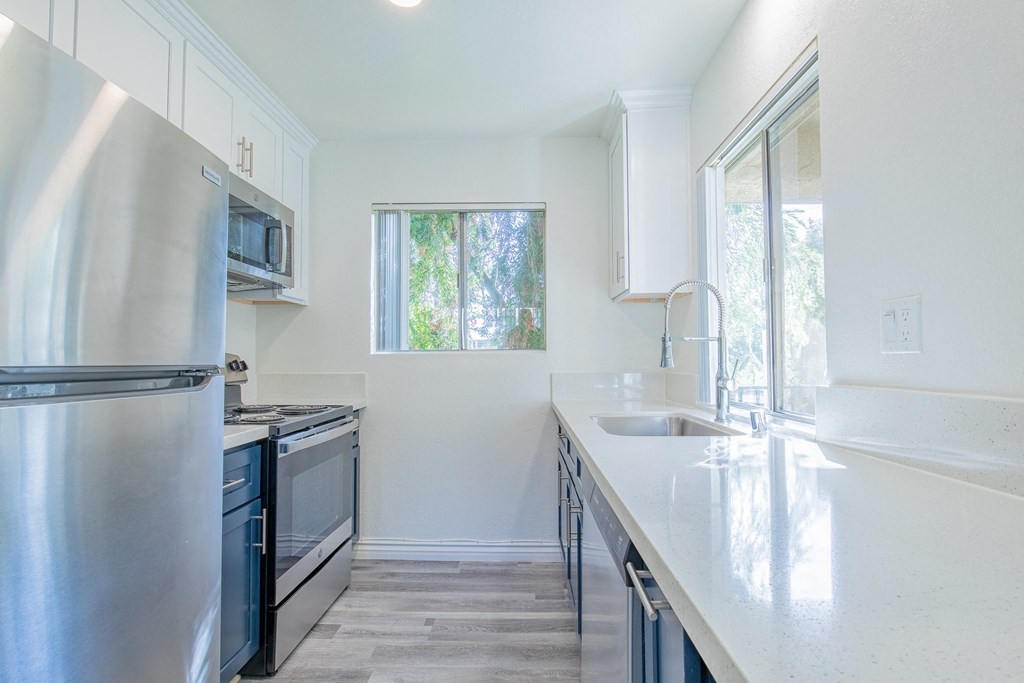 A modern kitchen with stainless steel appliances and white countertops.