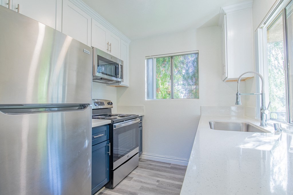 A kitchen with a stainless steel refrigerator, microwave, oven, and sink.