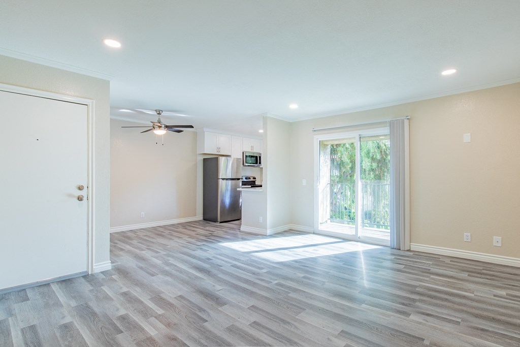 A spacious room with a ceiling fan and a refrigerator.