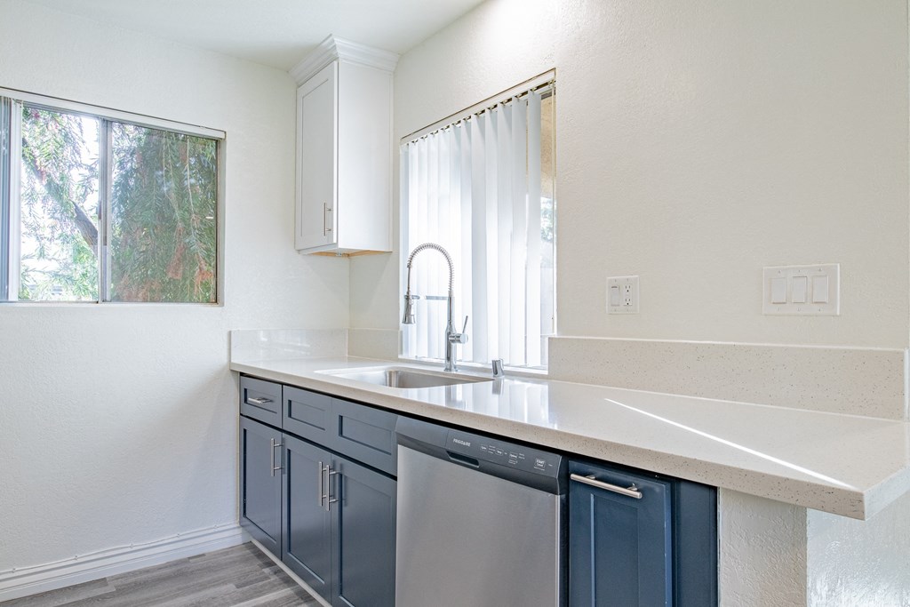A kitchen with a white counter top and blue cabinets.