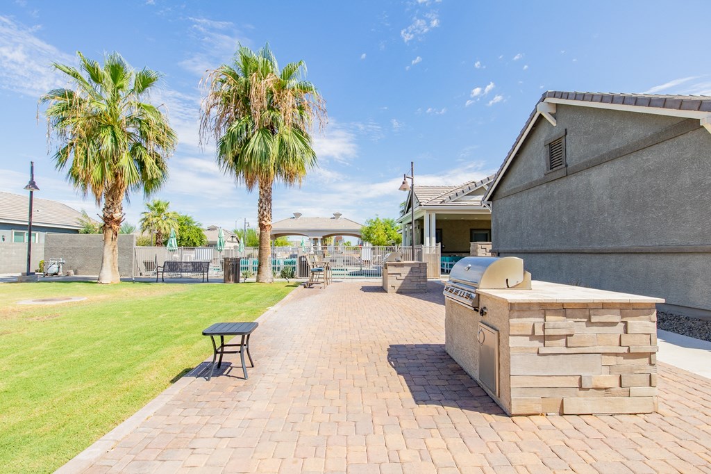 the backyard has a grill and a picnic table and palm trees