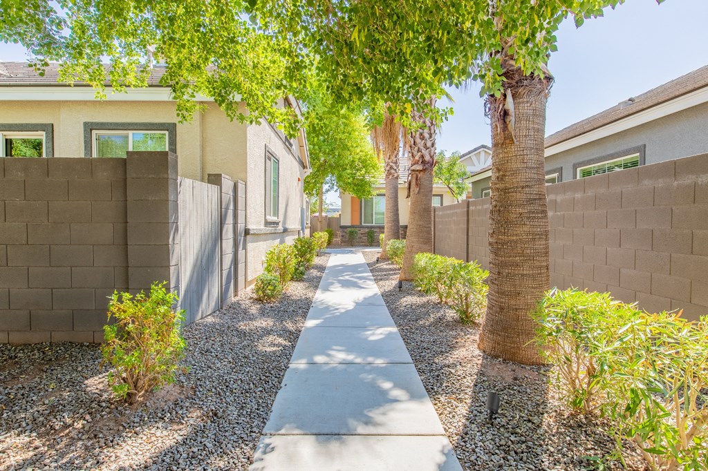 a long walkway with trees in front of a house