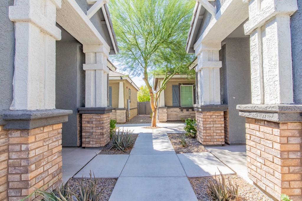 a walkway between two buildings with a tree in the middle