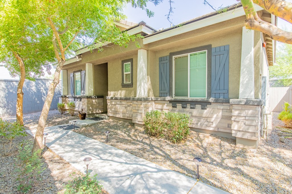 a house with green shutters and a sidewalk in front of it