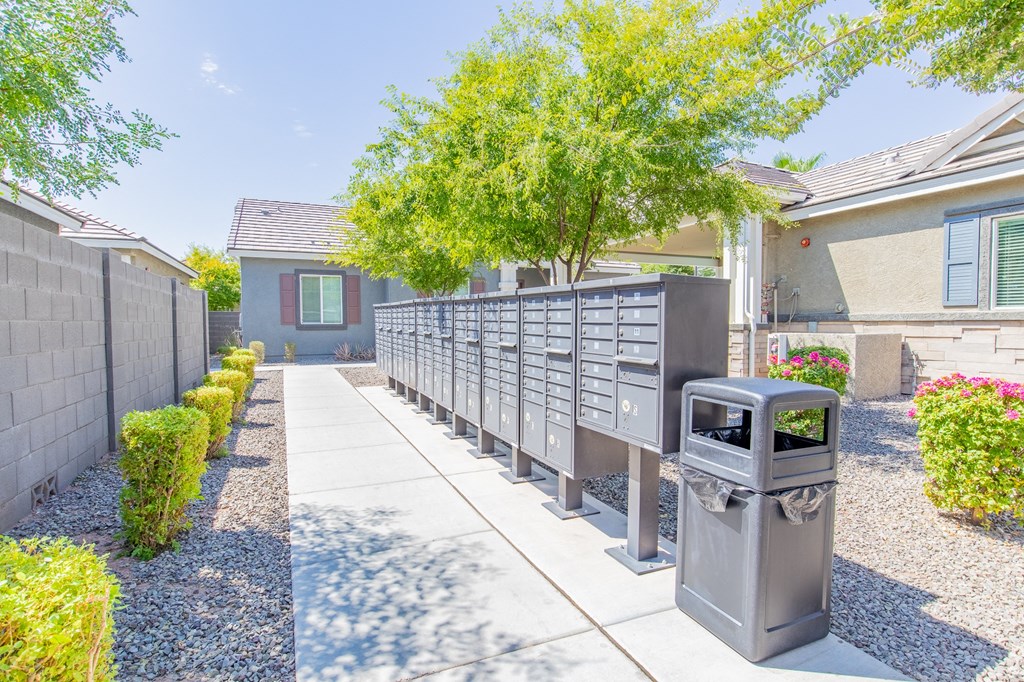 a driveway with a fence and a trash can in front of a house