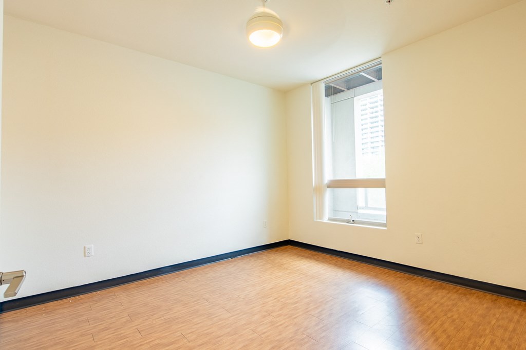 an empty room with wood flooring and a window