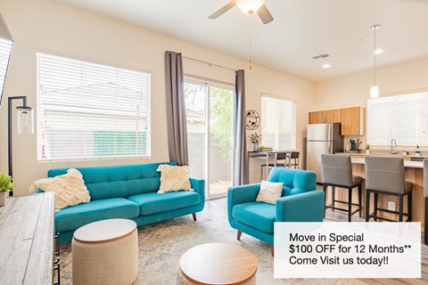 a living room with a blue couch and a kitchen with a table and chairs