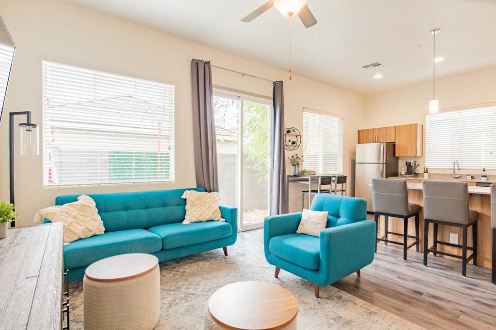 a living room with blue couches and a kitchen with a table and chairs