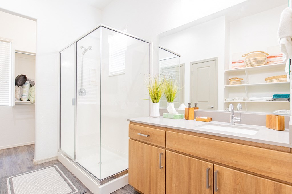 a bathroom with a shower and a sink and wooden cabinets