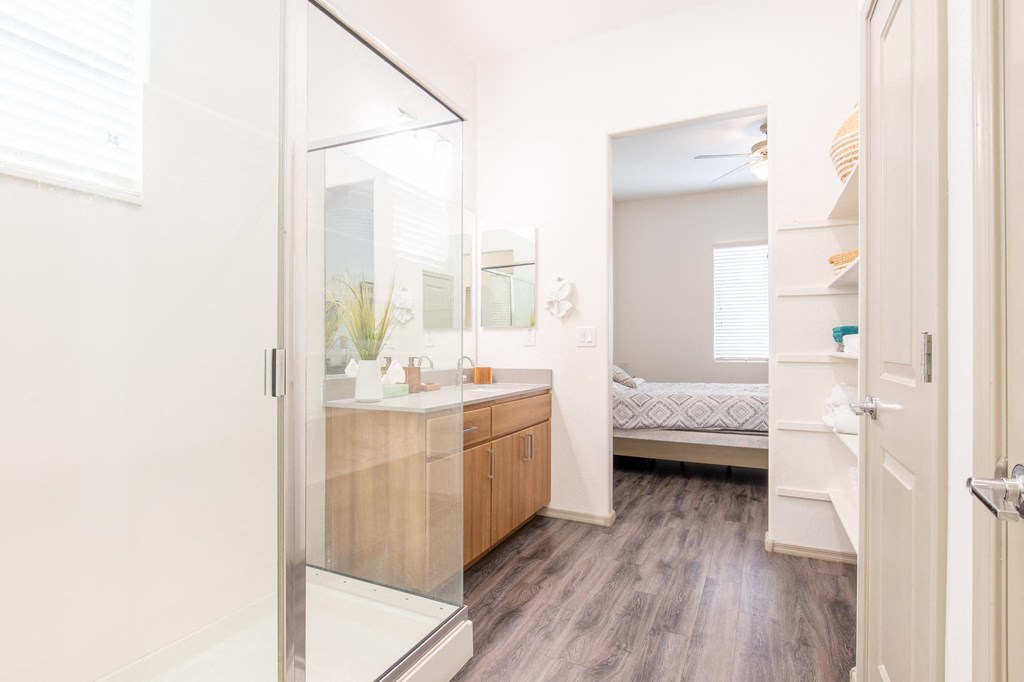 a bathroom with a shower and a sink and a bedroom