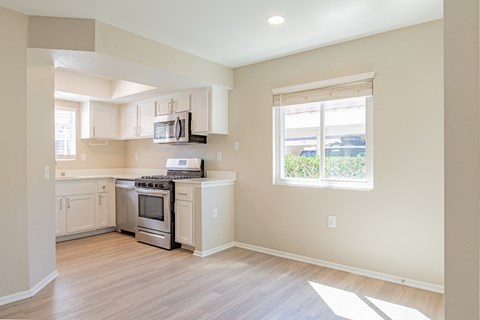 an empty kitchen with white cabinets and a window