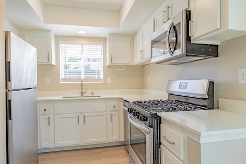 a kitchen with white cabinets and a stove and a refrigerator