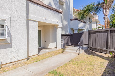 the front yard of a white house with a sidewalk and a wooden fence