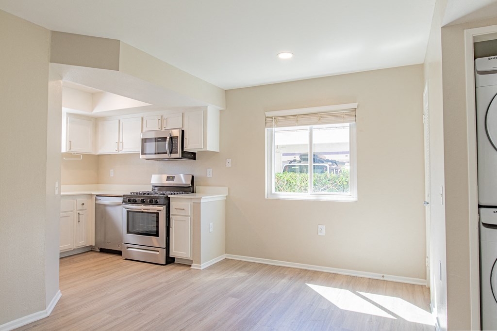 an empty kitchen with white appliances and a window