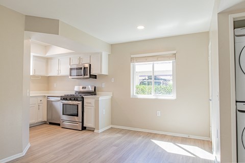 an empty kitchen with white appliances and a window