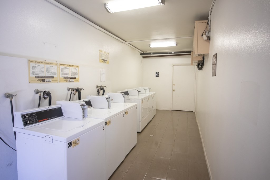 a laundry room with four washers and dryers and a row of washing machines