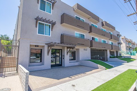 A modern building with a balcony and a green lawn in front.