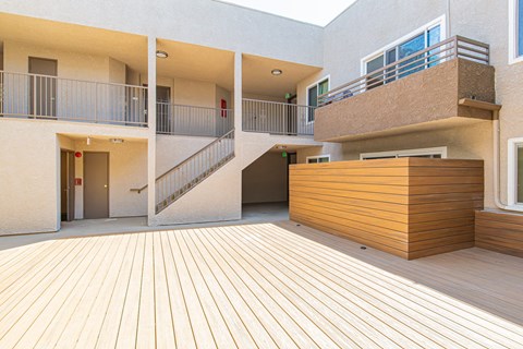 a courtyard with a wooden deck and a building with stairs