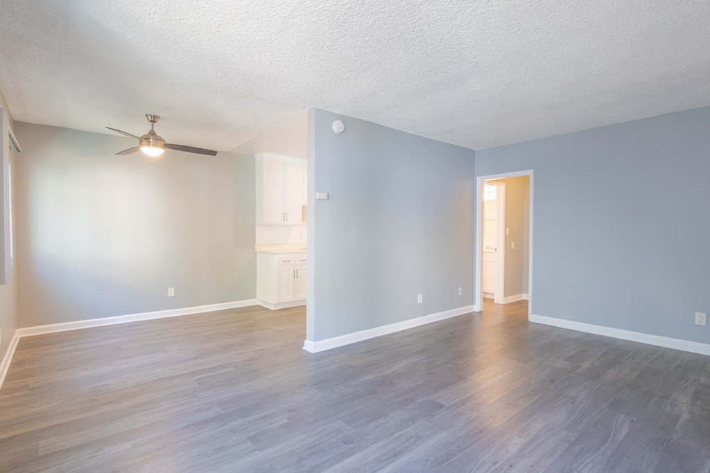 an empty living room with blue walls and a ceiling fan