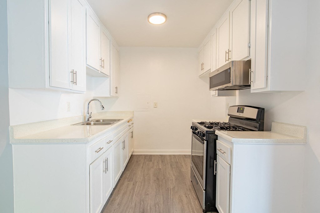a kitchen with white cabinets and a stove and a sink