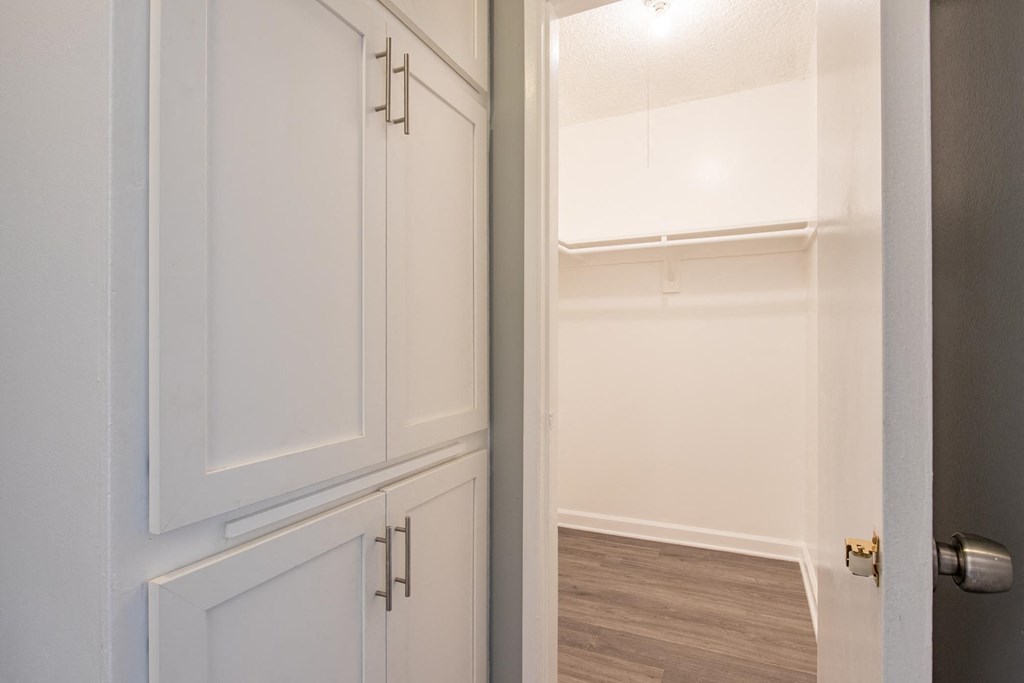 the closet in a small room with white cabinets and a door