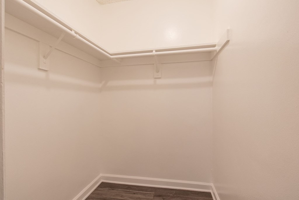 an empty room with white walls and a white shelf in the corner