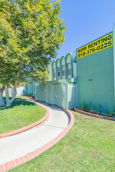 a sidewalk in front of a building with a sign for now renting