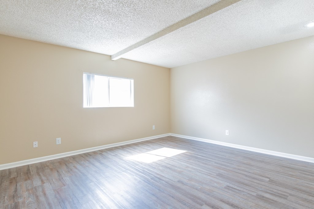an empty living room with wood floors and a window