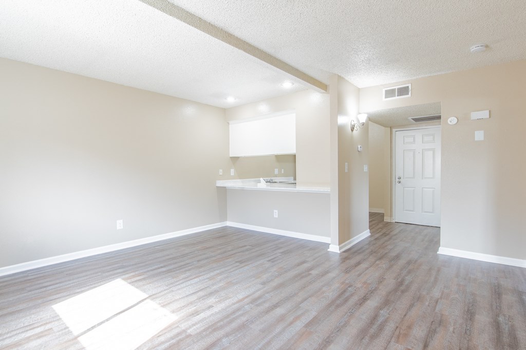 an empty living room and kitchen with wood flooring