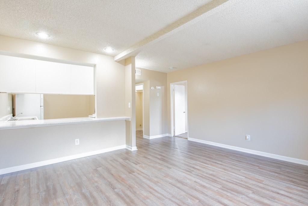 an empty living room and kitchen with a wood floor