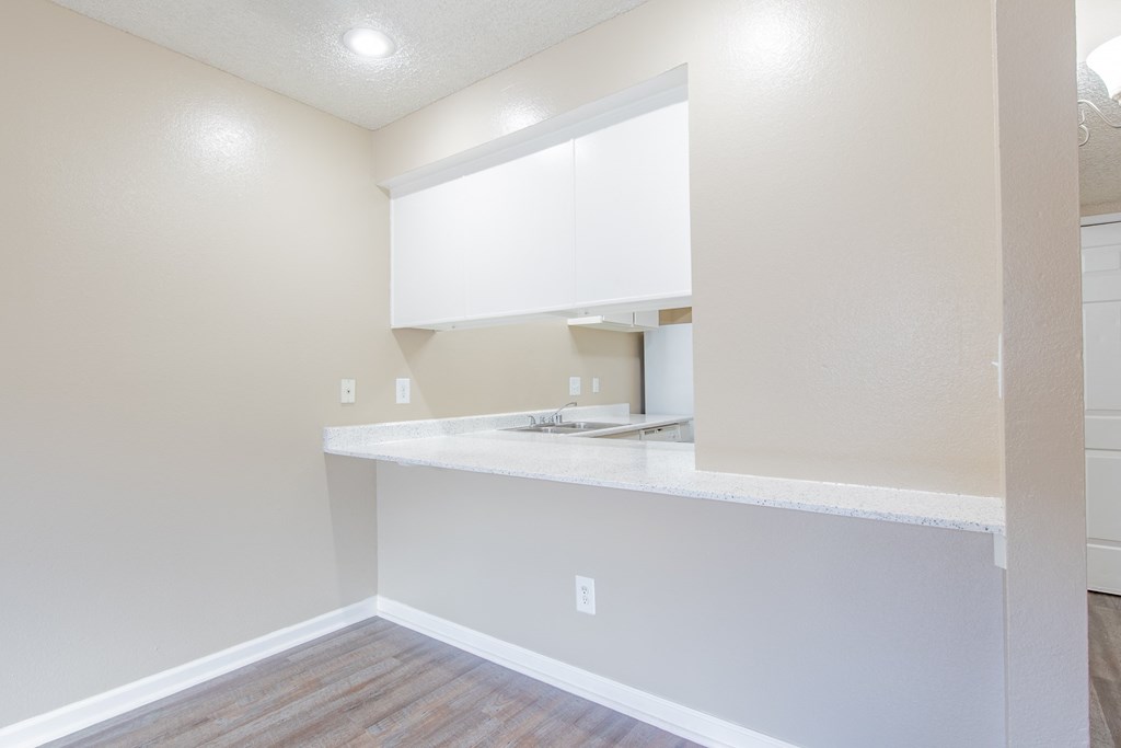 an empty kitchen with white cabinets and a counter top