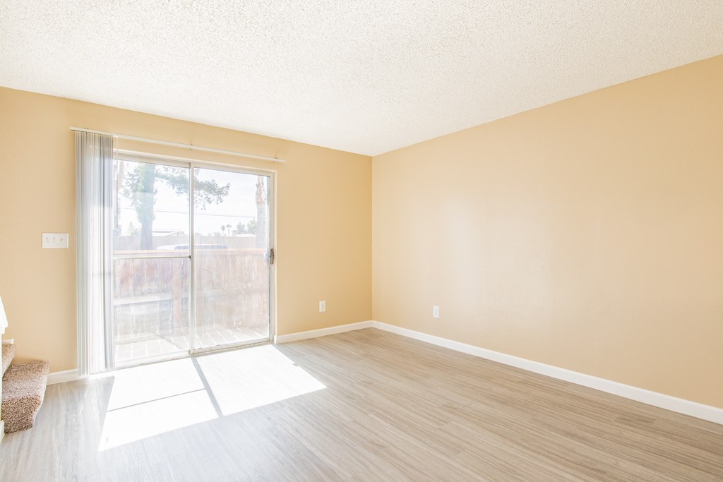 an empty living room with a sliding glass door to a patio