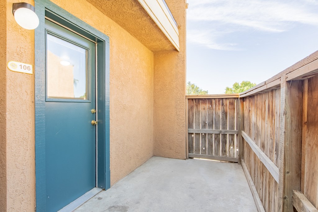 the balcony has a blue door and a wooden fence
