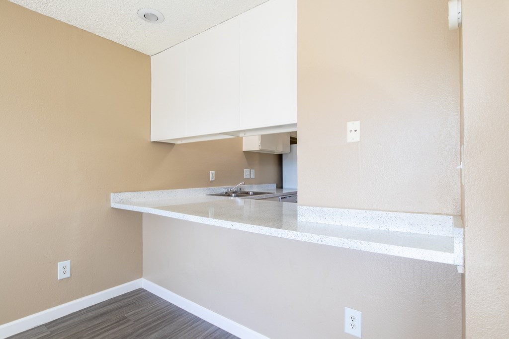 an empty kitchen with white cabinets and a counter top