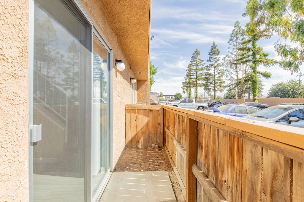 the balcony has a wood railing and a glass door