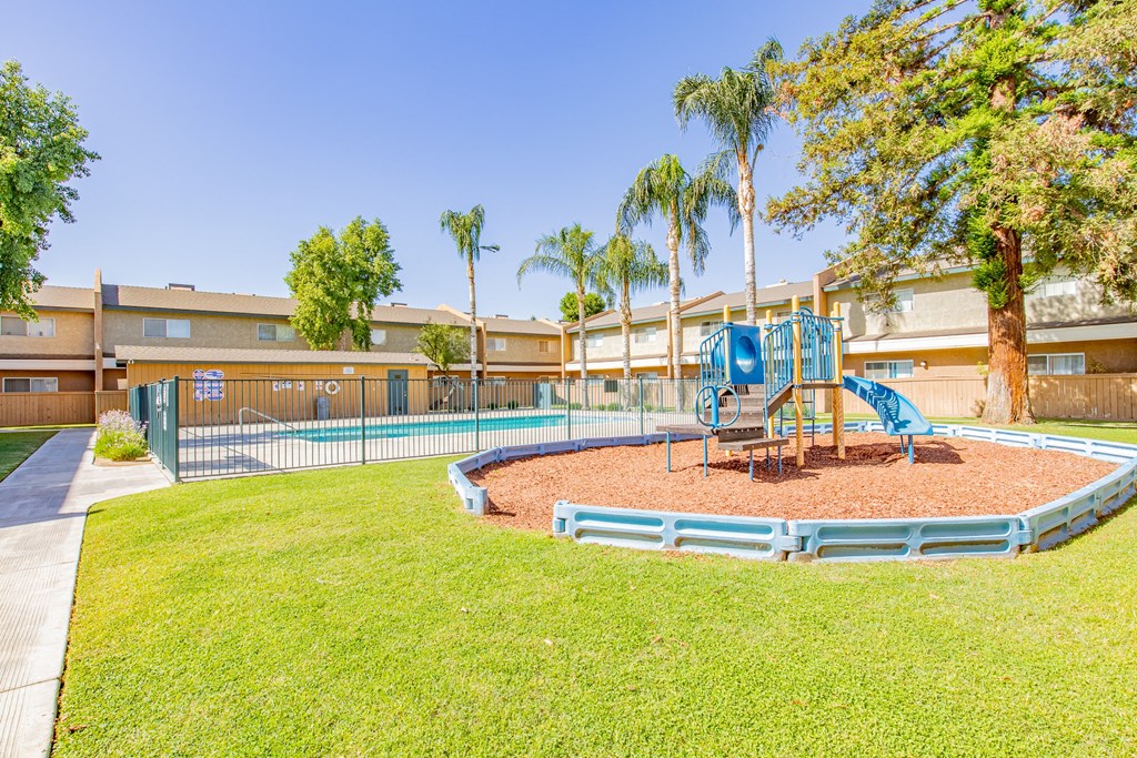 a playground with a blue playset in the grass