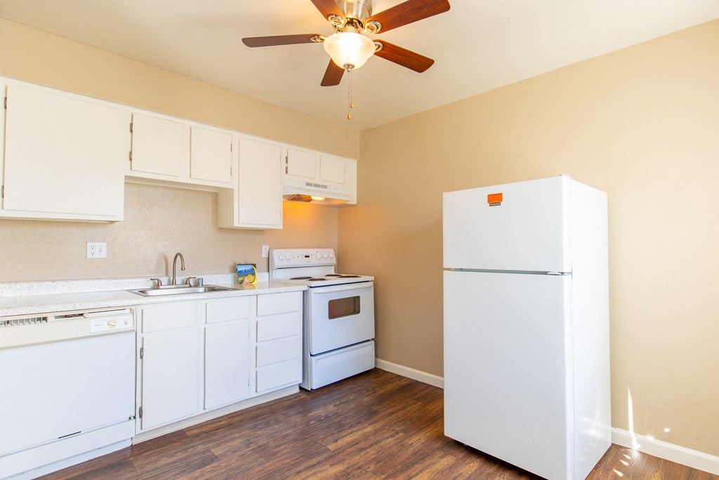 a kitchen with white appliances and a ceiling fan