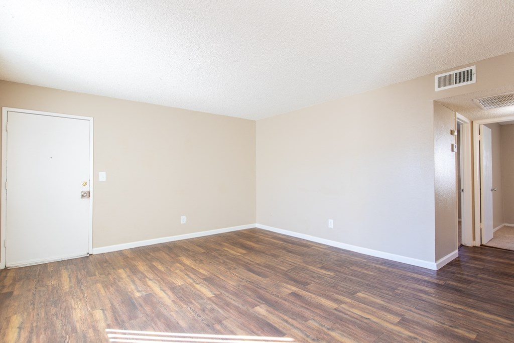 an empty living room with a hard wood floor and white walls
