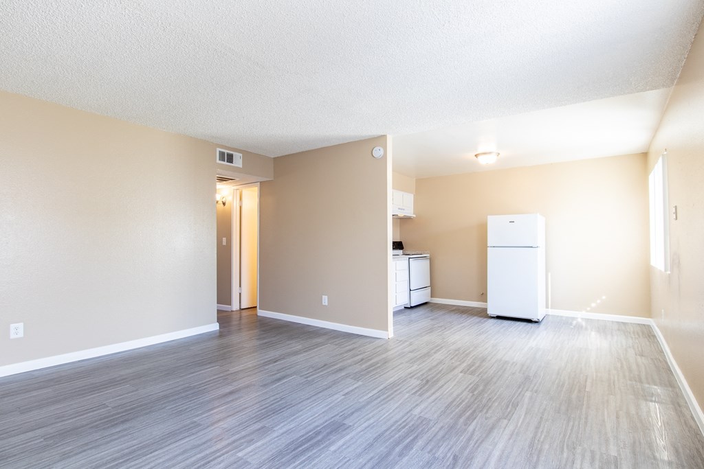 an empty living room and kitchen with a refrigerator and