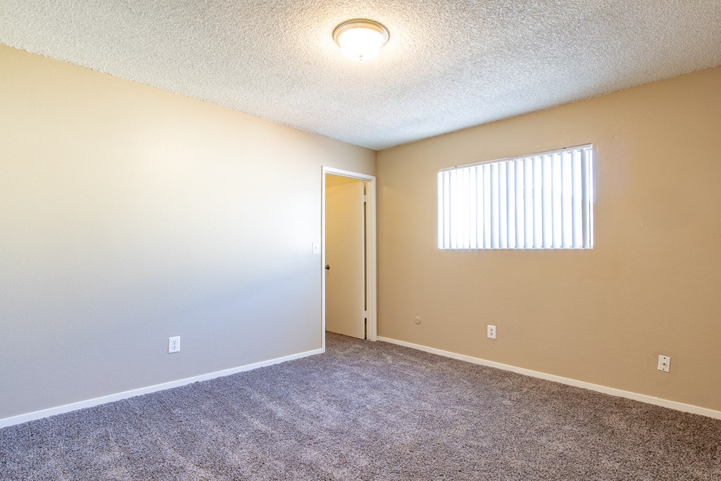 an empty living room with a door to a hallway and a window