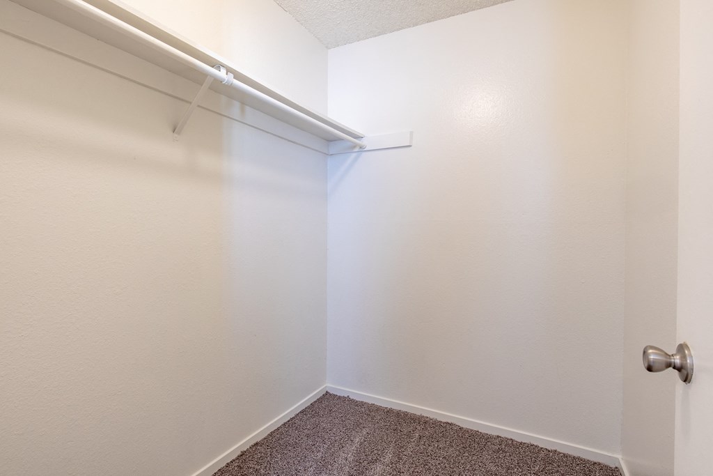 an empty closet in a room with white walls and carpet