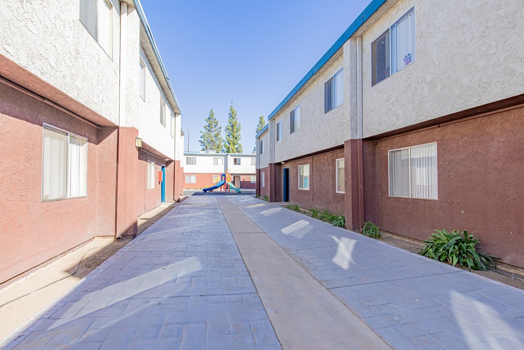 an empty alley between two buildings with a blue sky